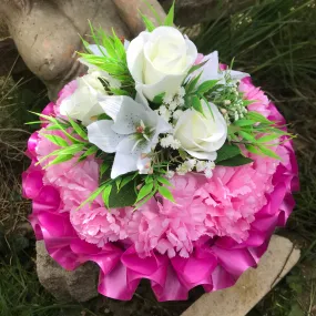 a funeral posy of artificial silk roses and lilies in shades of pink and white